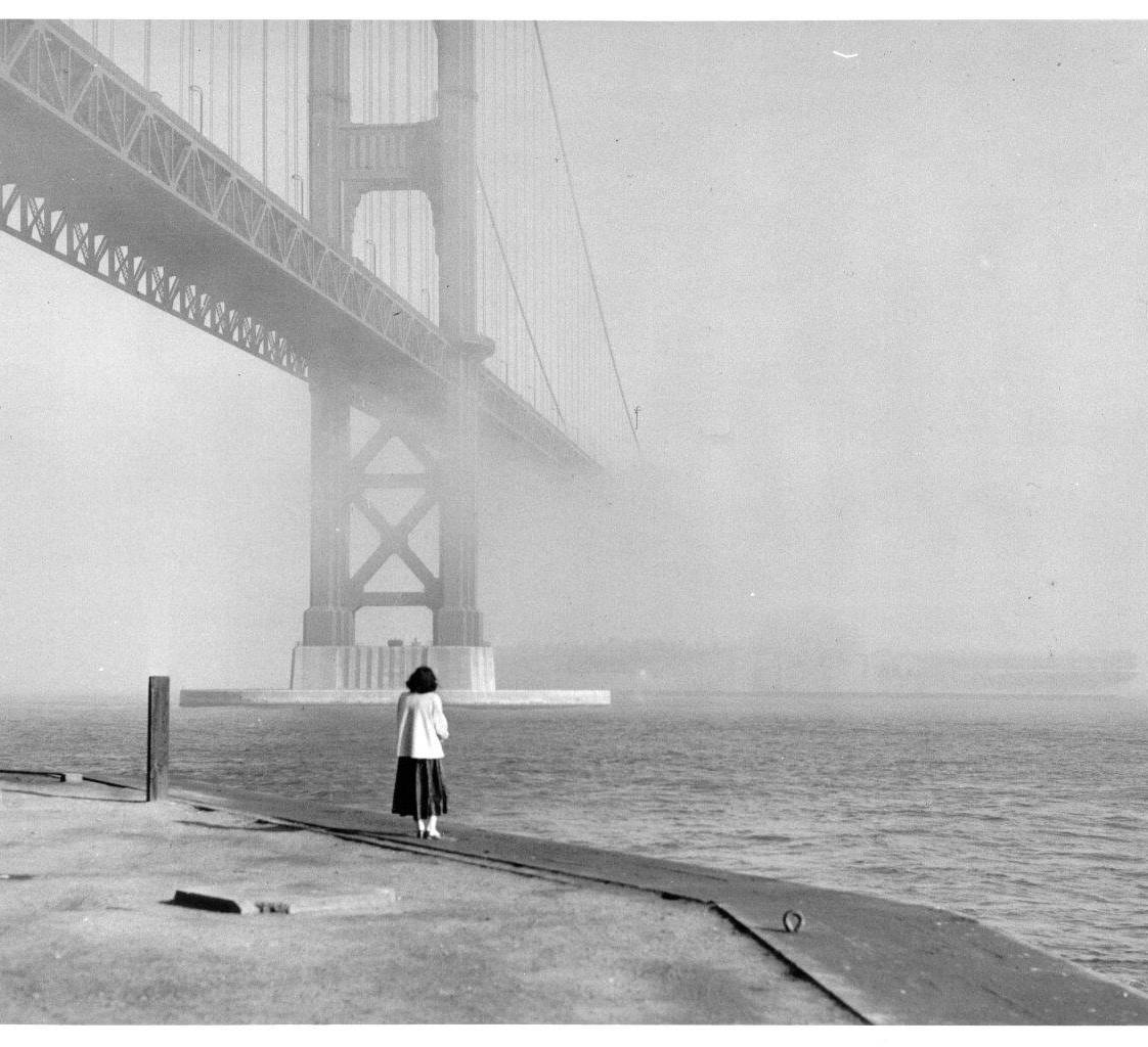 A lone figure on the shoreline beneath the Golden Gate Bridge, wrapped in San Francisco fog.